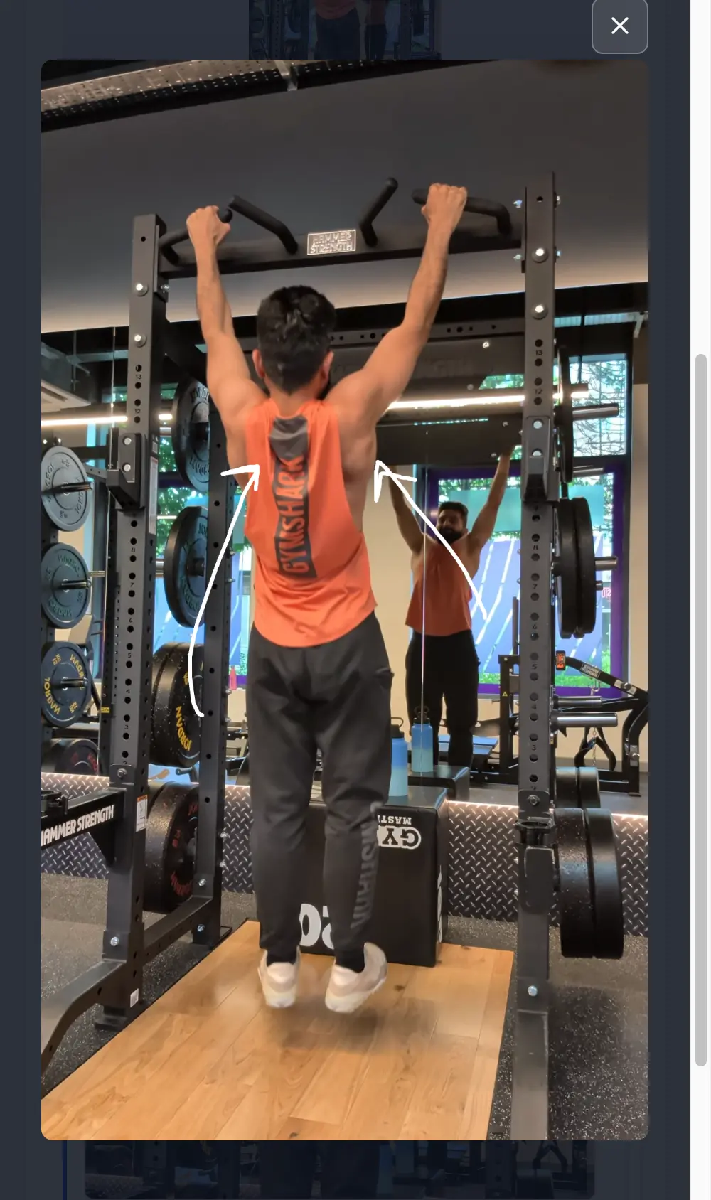 Full-screen view of a paused video frame with white arrows your coach drew on the shoulder blades, with a close button in the corner